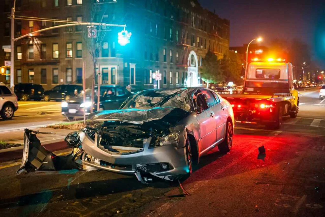 verunfalltes Fahrzeug im Vordergrund; im Hintergrund ein Abschleppwagen