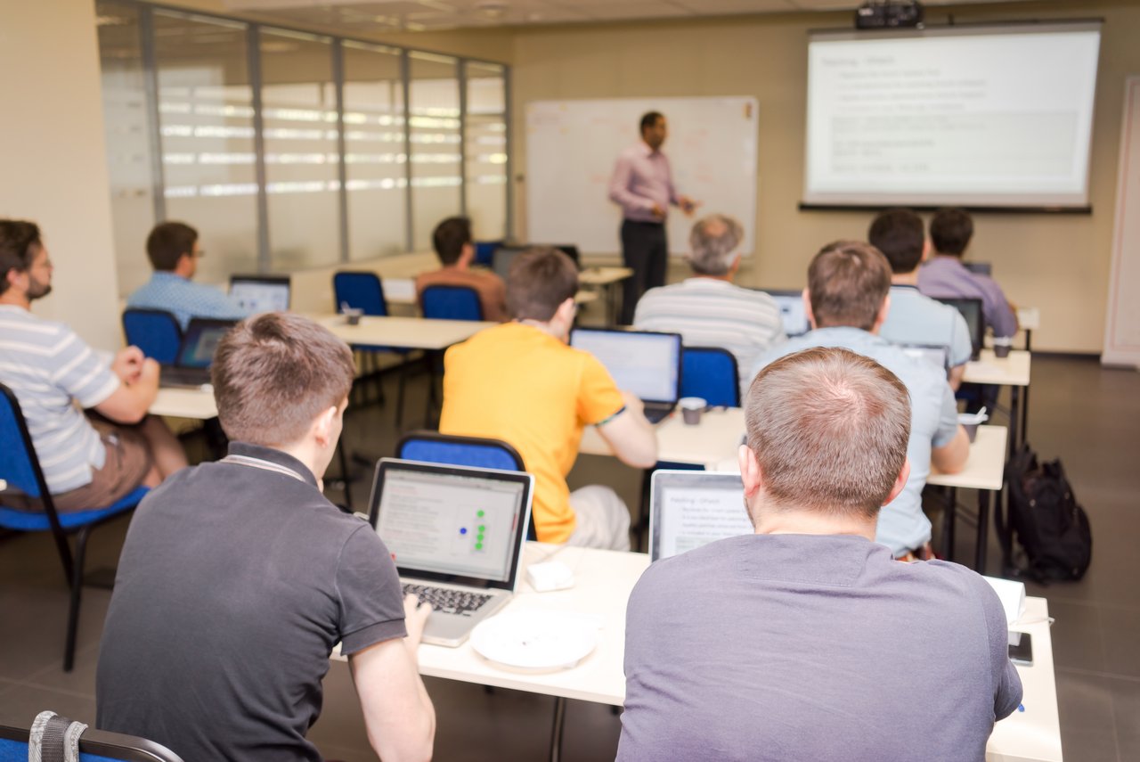 Lehrsaal mit Auszubildenden und Lehrer vor der Tafel